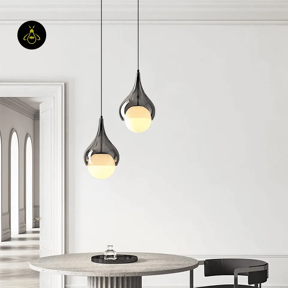 Smoked Glass Teardrop Pendant Light – 20 cm Hanging Bedside Light with Opal Globe 5 Two hanging bedside lights in smoked glass, hung at different heights over a round stone dining table