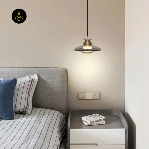 Gold-lustre borosilicate glass hanging light, Model A, glowing over a bedside table in a bedroom