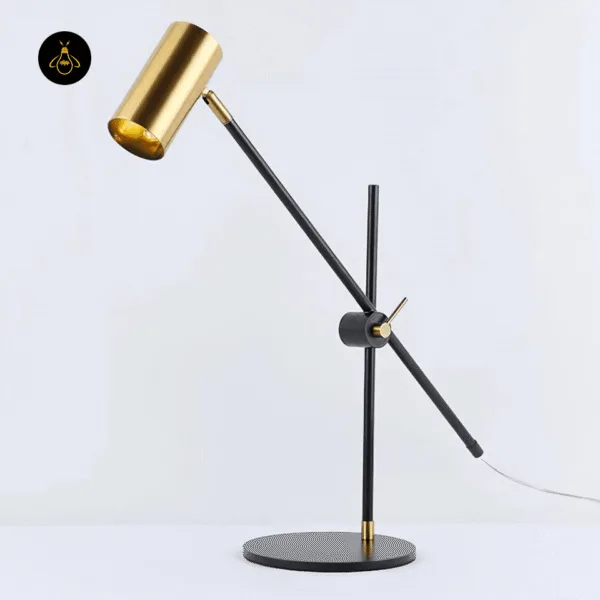 Gold-finish brass desk lamp with weighted black disc base on a desk