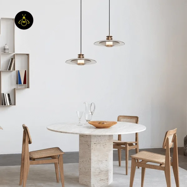 Two gold-lustre borosilicate glass hanging lights, Model A, over a round stone dining table with cane chairs