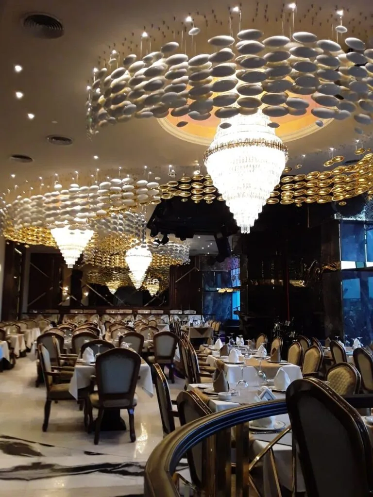 Dining room view with repeated shell-like ceiling lighting and crystal chandeliers in Hyderabad