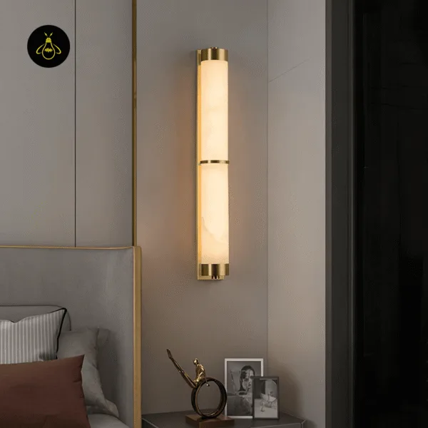 Alabaster wall light above a bedside table next to a grey upholstered headboard