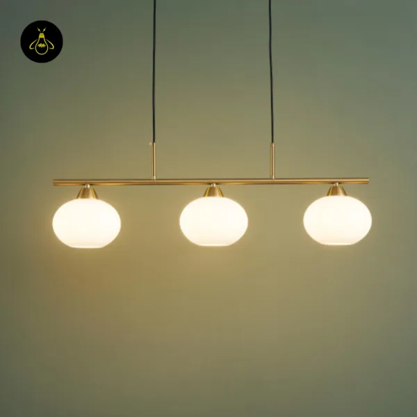 Linear pendant light glowing warm, three opal borosilicate glass globes against a green wall