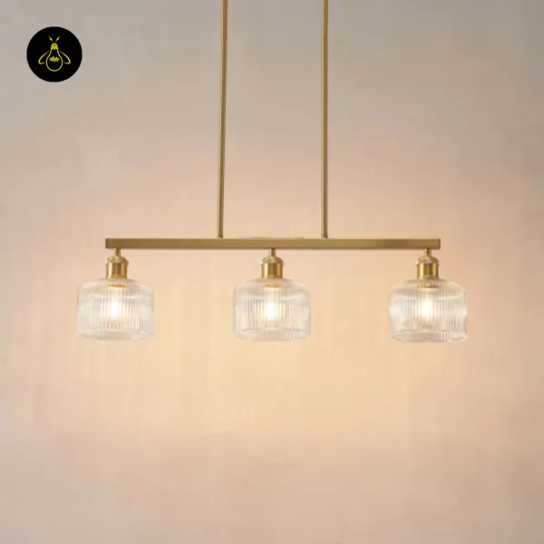Ribbed glass chandelier with three lit clear shades against a warm beige wall