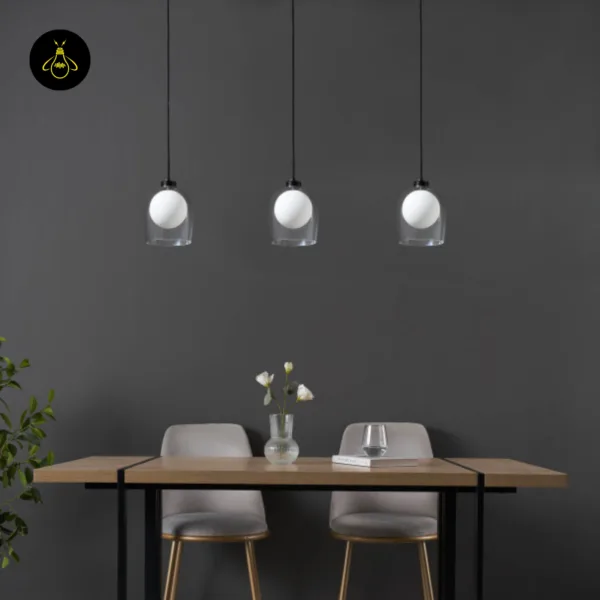 Three Calypso glass hanging lamps in a row over a wooden dining table against a charcoal wall