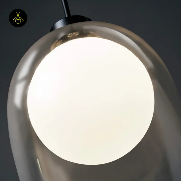 Close-up of the lit opal borosilicate glass globe inside the clear glass bell of the glass hanging lamp