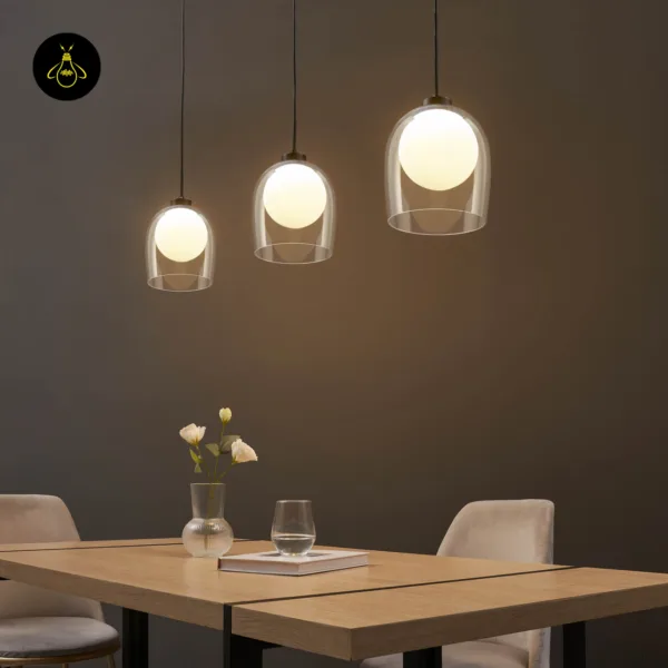 Three lit glass hanging lamps at different drops over a wooden dining table, opal globes glowing warm