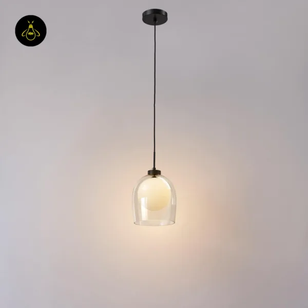 Glass hanging lamp on a black cord from a round matte black ceiling canopy, lit against a grey wall