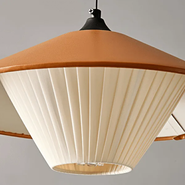Close-up of the cream pleated fabric diffuser under the orange cone of the kitchen island pendant light