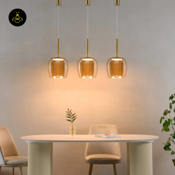 Three bell pendant lights lit in a row above a white dining table