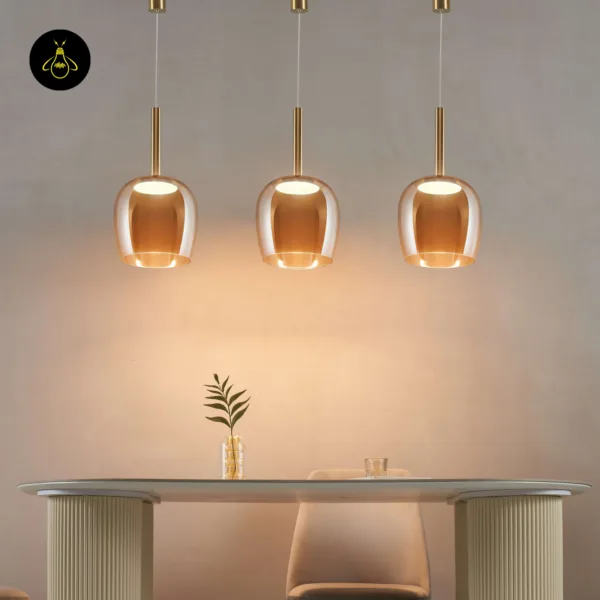 Three bell pendant lights lit low over a long white dining table, close view