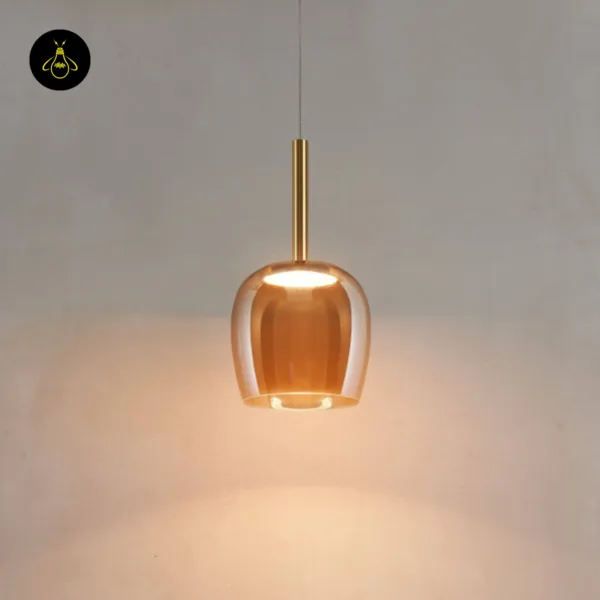 Bell pendant light lit against a grey wall, warm light falling from the amber borosilicate glass bell