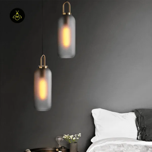 Two smoked glass pendant light shades glowing warm beside a bed against a dark grey wall