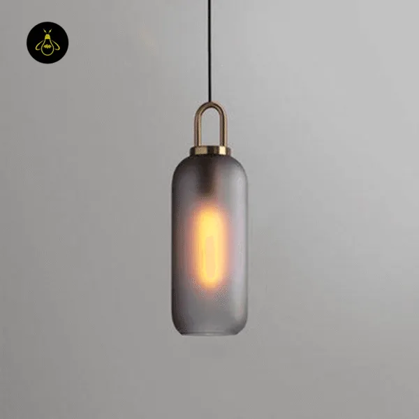 Matte smoked glass pendant light glowing warm, with a brass-finish loop cap, on a grey wall