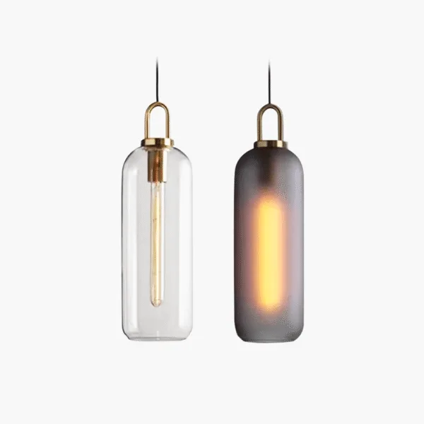 Glass pendant light in two options: a clear borosilicate glass capsule with a tube bulb and a matte smoked capsule glowing, both with brass-finish caps