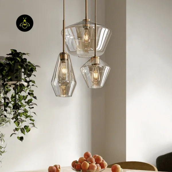 Three amber glass pendant lights hung as a cluster over a dining table with a bowl of peaches