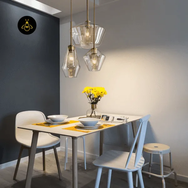 Cluster of three amber glass pendant lights over a small white dining table with yellow flowers