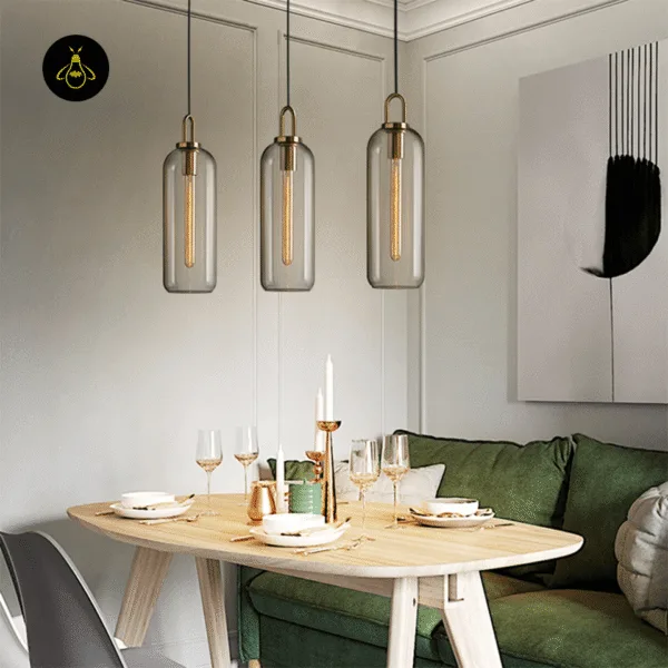 Three clear glass pendant light capsules hanging in a row over a wooden dining table