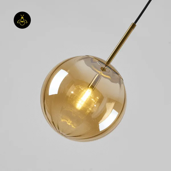 Close-up of a lit gold-lustre globe hanging light showing the stem, cap and bulb inside
