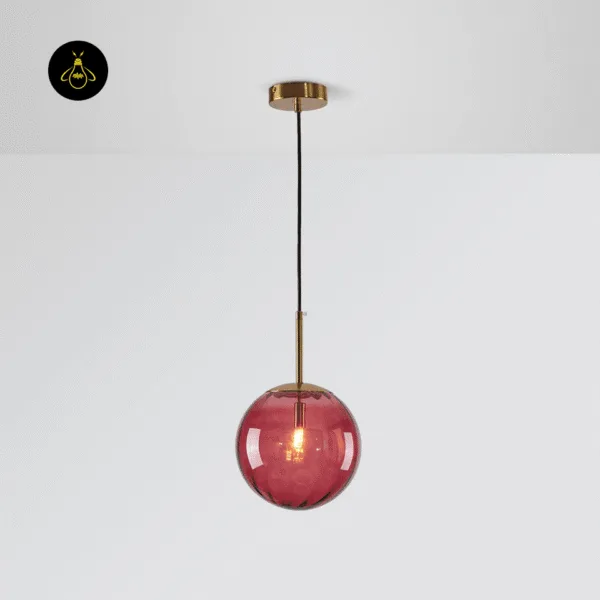 Pink globe hanging light switched on, ribbed pink borosilicate glass on a brushed gold stem
