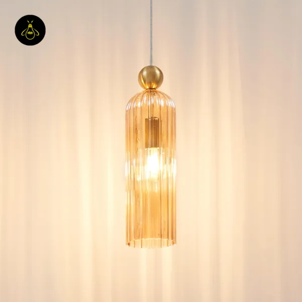 Fluted pendant light switched on, amber borosilicate glass glowing around an E27 bulb under a gold-finish ball