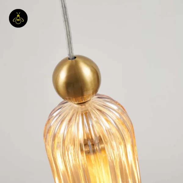 Close-up of the brushed gold-finish stainless steel ball and clear cable on top of the fluted pendant light