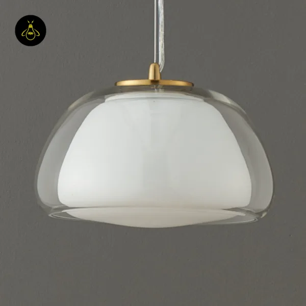 Lomelia double glass pendant light switched off against a grey wall, white opal inner shade inside the clear outer dome, gold-finish cap