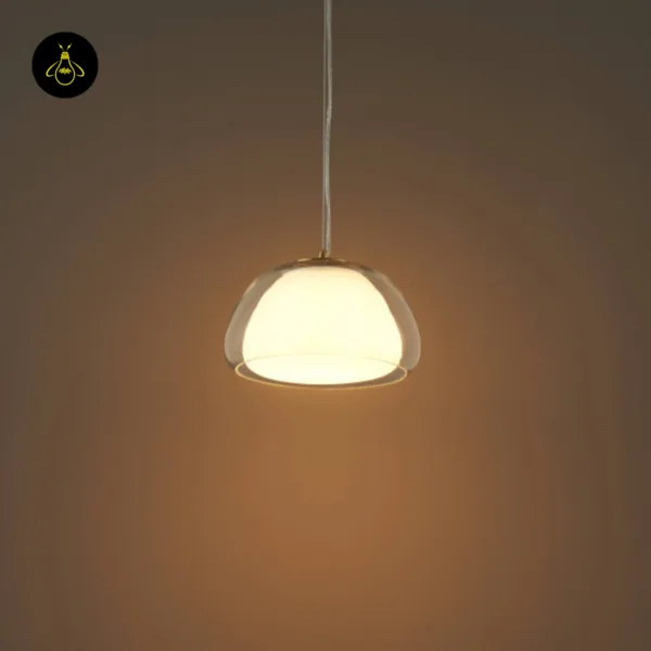 Lomelia double glass pendant light lit in a dark room, 25 cm dome on a transparent cord casting a warm pool of light