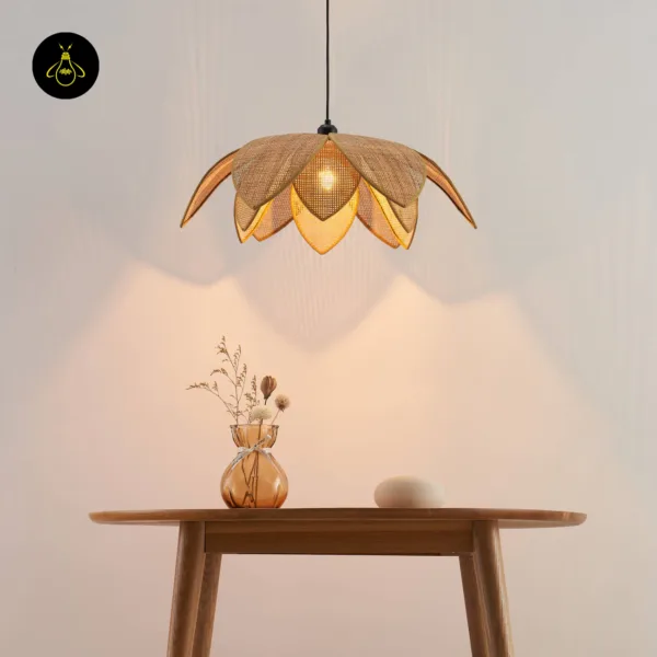 Cane pendant light lit over a round wooden table with a vase and a cane-back chair