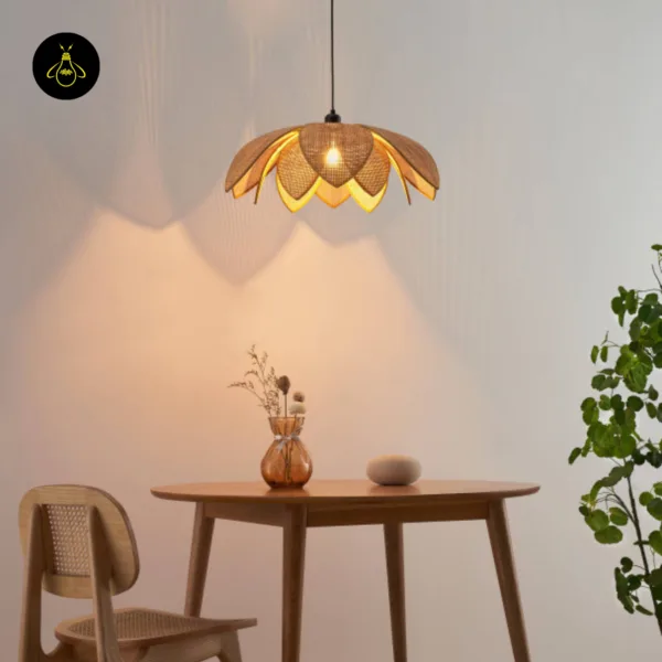 Cane pendant light lit above a round wood dining table with a vase and stone