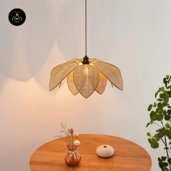 Cane pendant light glowing over a round wooden table, with a plant beside it