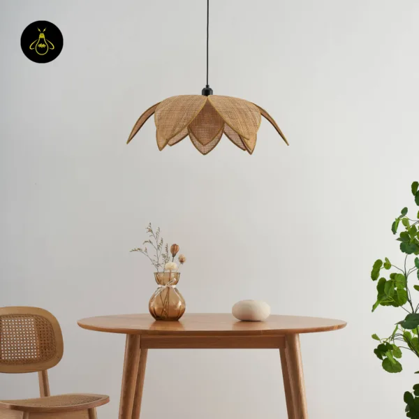 Unlit cane pendant light above a round wooden dining table beside a cane chair and a plant