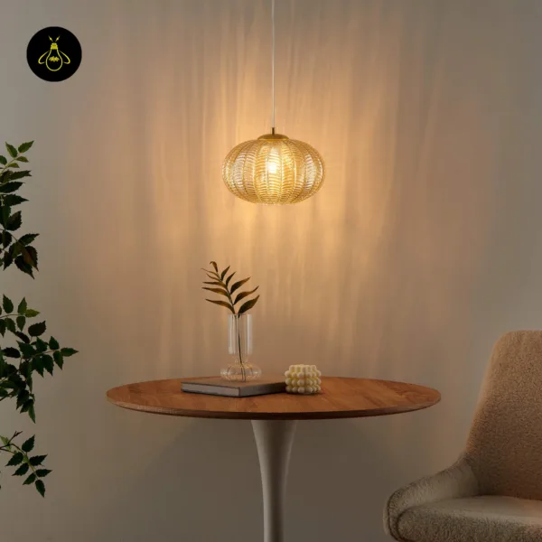 Textured glass pendant light casting warm amber light over a round wooden table and vase