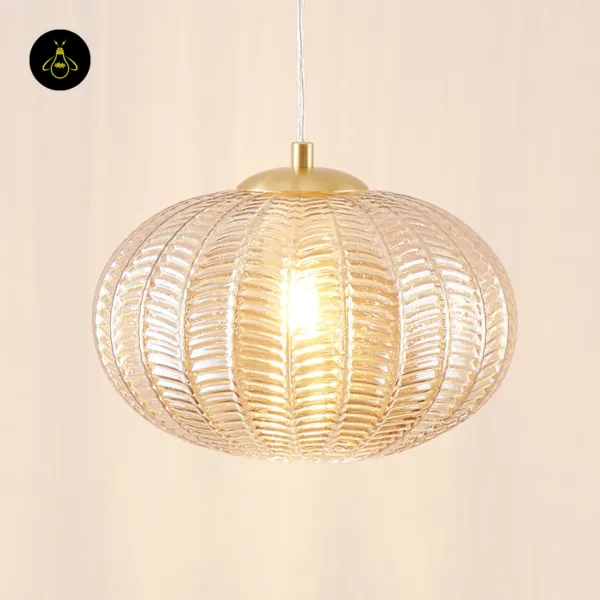 Lit textured glass pendant light with a brass-finish stainless steel cap on a clear cord