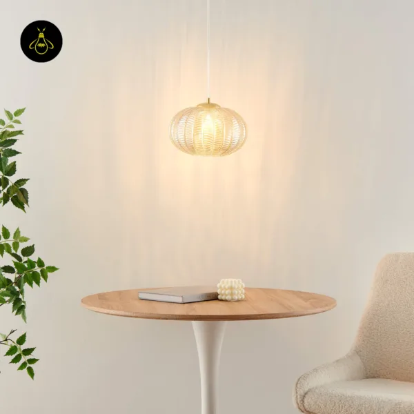 Textured glass pendant light over a round wooden table beside a cream chair and a green plant