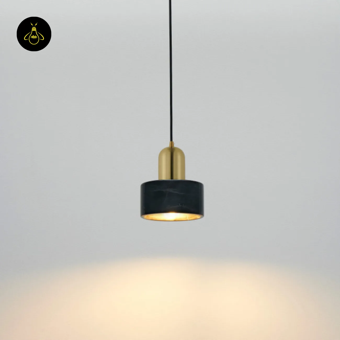Black Marble Pendant Light – Meryl | 15 cm Marble Hanging Light with Gold Cap 3 Marble hanging light lit against a grey wall, throwing a warm pool of light downward
