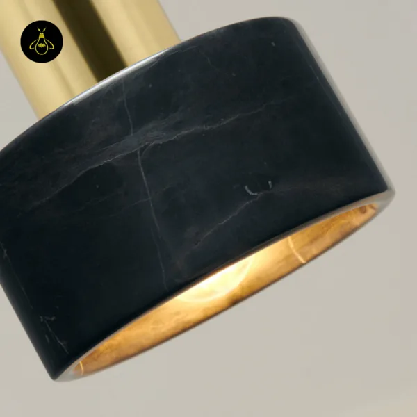 Close-up of the marble hanging light showing natural pale veins in black marble and the gold inner lining