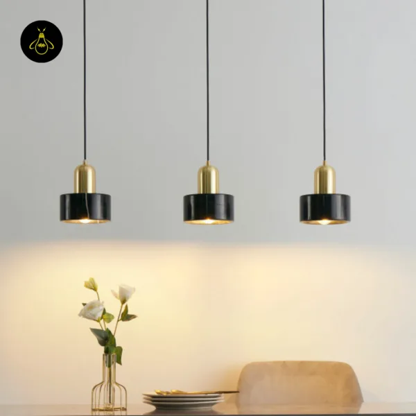 Three black marble hanging lights in a row above a dining table with flowers and plates