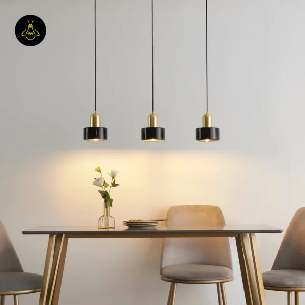 Three marble hanging lights over a grey dining table with velvet chairs