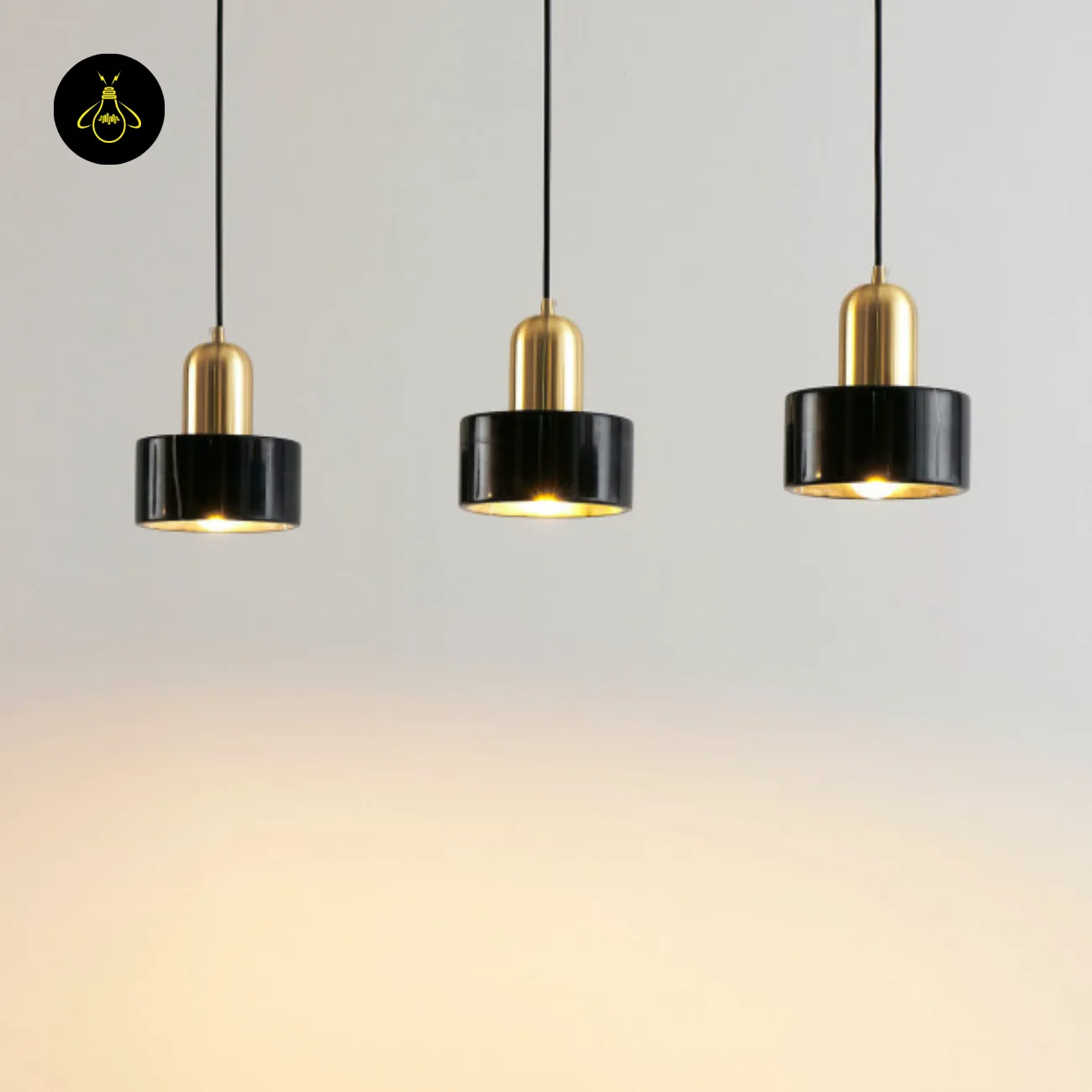 Black Marble Pendant Light – Meryl | 15 cm Marble Hanging Light with Gold Cap 7 Three black marble pendants with gold caps glowing warm against a pale wall