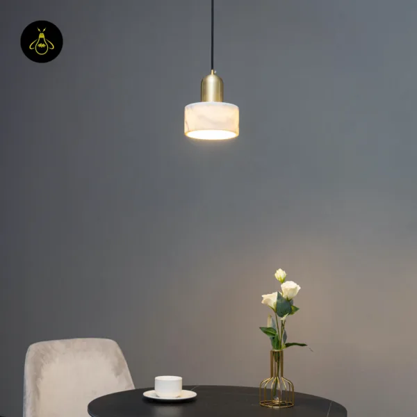 Meryl marble light glowing above a round café-style table beside a grey velvet chair