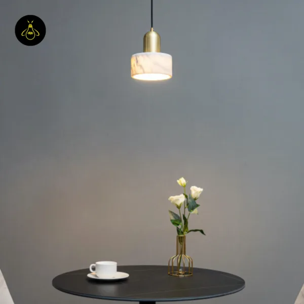 Marble light lit over a round black dining table with a coffee cup and white flowers