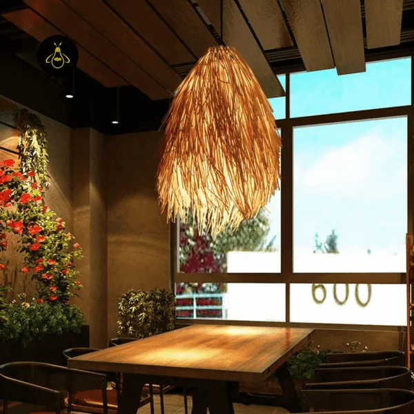 Rattan pendant light lit above a wooden dining table beside a large window in a café