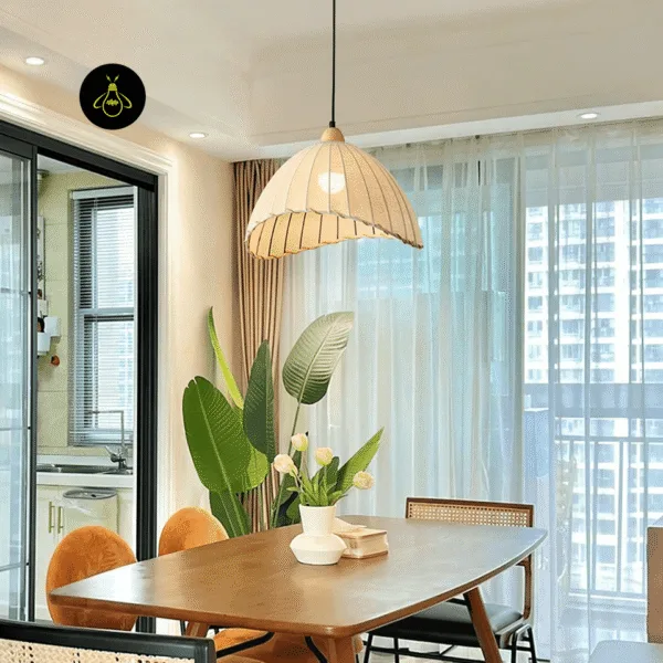 Linen cloth pendant light over a wooden dining table beside sheer curtains and a tall plant