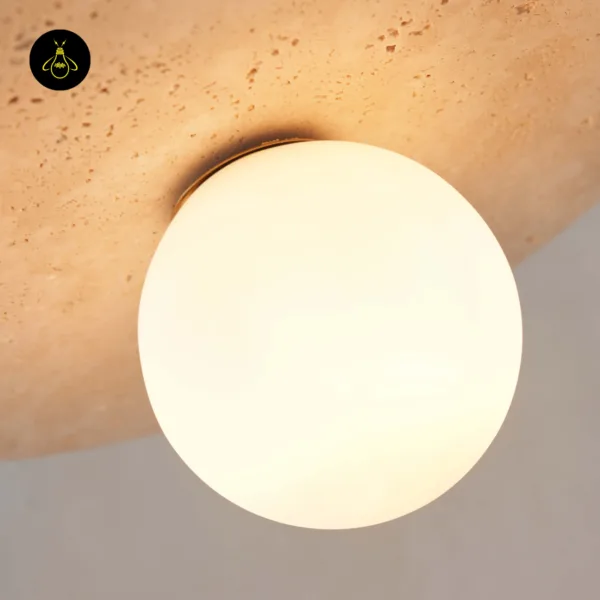 Close-up of the lit opal borosilicate glass globe under the travertine disc of a stone pendant light