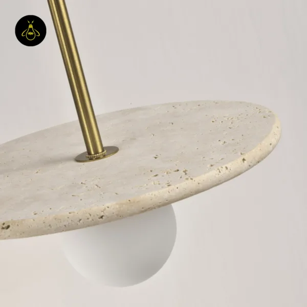 Stone pendant light seen from above, the brass-finish stainless steel stem meeting the honed travertine disc