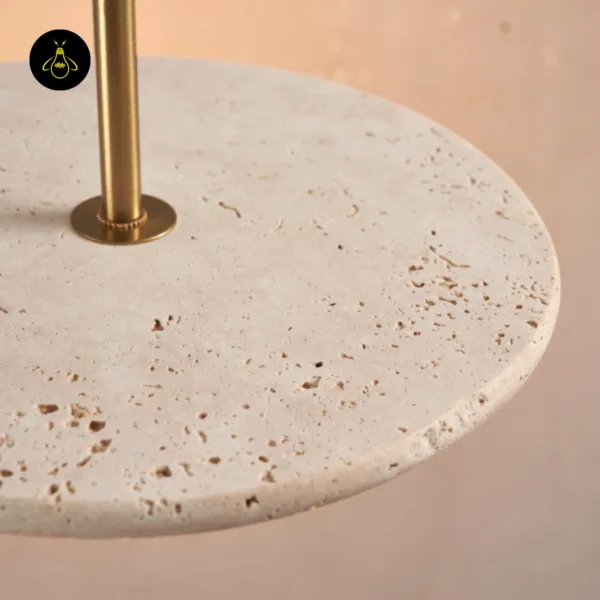 Close-up of natural travertine pores and the brass-finish collar on a stone pendant light