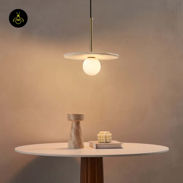 Stone pendant light glowing over a round table with a stone vase and a book