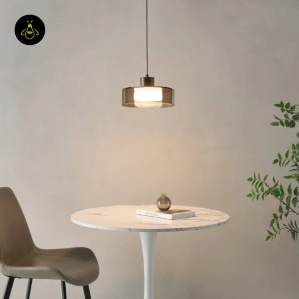 Smoked glass drum pendant light hanging over a small round marble dining table