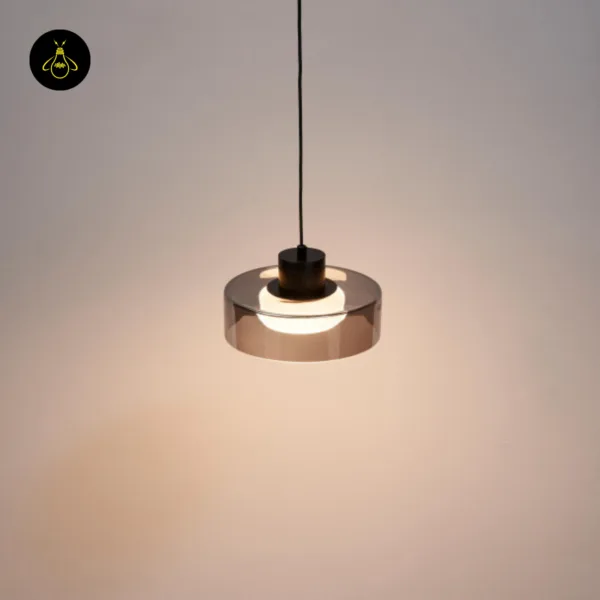 Smoked glass drum pendant light casting a warm glow on a wall